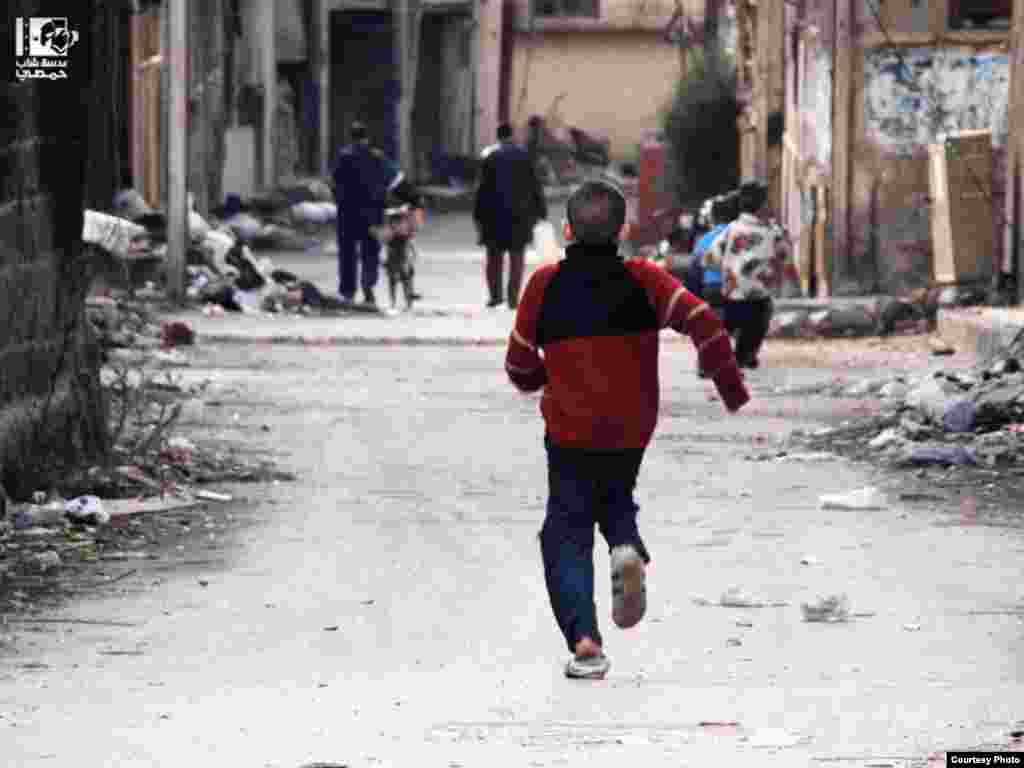 2013年1月26日，敘利亞男孩在霍姆斯的波斯坦.德萬街奔跑。 (Lens Young Homsi)