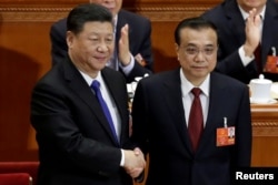 中国总理李克强在北京人大会堂召开的全国人大会议上获连任后与中国国家主席习近平握手。（2018年3月18日）