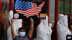 Một người Việt đeo khẩu trang biểu tình đòi thống đốc California cho phép mở cửa lại các tiệm làm móng trước trung tâm thương mại Phước Lộc Thọ, thành phố Westminster, California, ngày 8 tháng 6, 2020.
