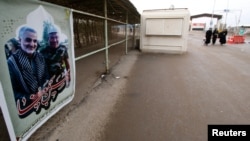 FILE - A poster with a picture of a martyr, member of Shiite Popular Mobilization Forces with Iranian Revolutionary Guard Commander Qassem Soleimani is seen at Iraqi side of the Shalamcha Border Crossing, Iraq, Nov. 4, 2018.