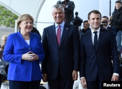 FILE - German Chancellor Angela Merkel, left, and French President Emmanuel Macron welcome Kosovo's President Hashim Thaci, center, to a meeting with Western Balkans leaders, at the Chancellery in Berlin, Germany, April 29, 2019.