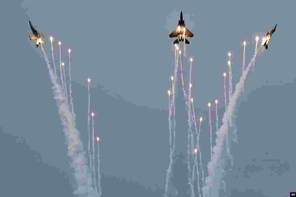 An F-15SG fighter jet, center, along with two F-16 fighter jets on either side from the Republic of Singapore Air Force perform a maneuver with pyrotechnics during an aerial display preview ahead of the Singapore Airshow.