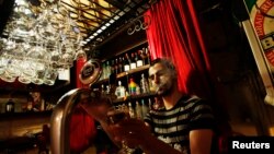 Bartender Samet Kardas smokes as he serves beer at a bar in Istanbul, Turkey, Jul. 14, 2009. 