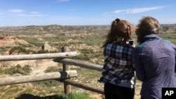 Jeanne Randall and her daughter Zoe, of Shoreview, Minn., take photos at Painted Canyon in Theodore Roosevelt National Park in western North Dakota, May 24, 2017. A company wants to build an oil refinery about 3 miles from the park, but some worry about air pollution in the park. 