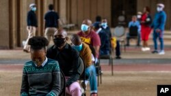 FILE: Off duty metro police officers sit on the chairs whilst queuing to be screened and tested for COVID-19 in Johannesburg, South Africa, Thursday, May 7, 2020. South Africa begun a phased easing of its strict lockdown measures on May 1.