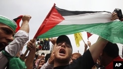 A Palestinian holds up a flag as he celebrates the reconciliation agreement between rival Palestinian factions Fatah and Hamas during a rally in Gaza City, May 4, 2011