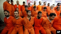 FILE - Handcuffed al-Qaida linked suspects sit in the terrorist combat and organized crime department in Baghdad, Iraq, Dec. 2, 2010.