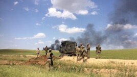 After taking back this field from IS, trucks plow down IS barriers to allow humvees to move into the fight, in Mosul, Iraq, May 4, 2017. (H. Murdock/VOA)