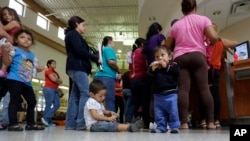 FILE - Immigrants who entered the U.S. illegally stand in line for tickets at the bus station after they were released from a U.S. Customs and Border Protection processing facility in McAllen, Texas. 