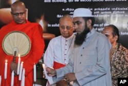A Sri Lankan Muslim priest, lights a candle as Buddhist priest, left, Hindu priest, right, and Christian archbishop, center, watch during a function to express solidarity with all the victims of Easter Sunday attacks, in Colombo, April 28, 2019.