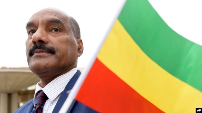 FILE - Negasi Beyene, who grew up in Mekele, the capital city of the Ethiopia's Tigray Region, holds a traditional Ethiopian flag, Dec. 18, 2021, in Columbia, Maryland.