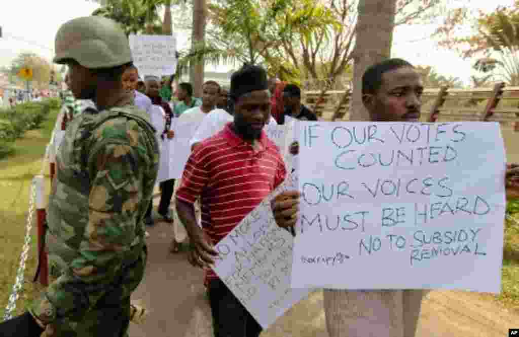 Protesters walk past a soldier standing guard during a rally against fuel subsidy removal in Nigeria's capital Abuja, January 6, 2012. Nigerians angered by the government's decision to remove fuel subsidies protested in the capital on Friday, showing dete