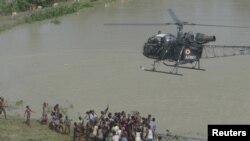 Sebagian korban bencana banjir di wilayah Sonitpur, negara bagian Assam, berkumpul di bawah helikopter Tentara India yang membawa bantuan untuk mereka (24/9).