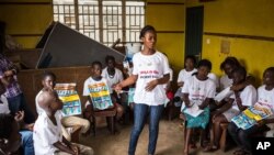 FILE - A charity worker, center, from the GOAL Ireland humanitarian agency, educates children on how to prevent and identify the Ebola virus in their communities at Freetown, Sierra Leone.