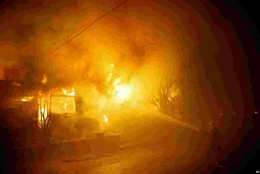 A firefighters battles the Getty fire as a home burns along Tigertail Road in Los Angeles, California.