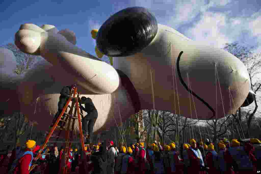 Workers prepare the giant Snoopy balloon before the 87th Annual Macy's Thanksgiving Day Parade, New York, Nov. 28, 2013. 