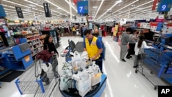 FILE- Walmart associate Luis Gutierrez, center, checks out a customer at a Walmart Supercenter in Houston, Texas, Nov. 9, 2018.