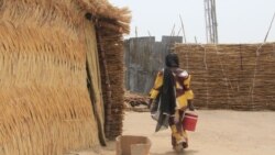 Une femme porte un seau d'eau au camp informel de Yawuri, à la périphérie de Maiduguri, capitale de l'État de Borno, le 29 mars 2021.