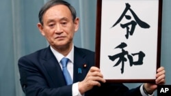 Japan’s Chief Cabinet Secretary Yoshihide Suga unveils the name of new era “Reiwa” at the prime minister’s office in Tokyo, Monday, April 1, 2019. 