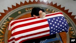 Cindy McCain, wife of Sen. John McCain, R-Ariz., lays her head on casket during a memorial service at the Arizona Capitol in Phoenix, Aug. 29, 2018. 