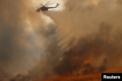 Un helicóptero lanza agua sobre un incendio en Orange, California. Oct. 9, 2017.