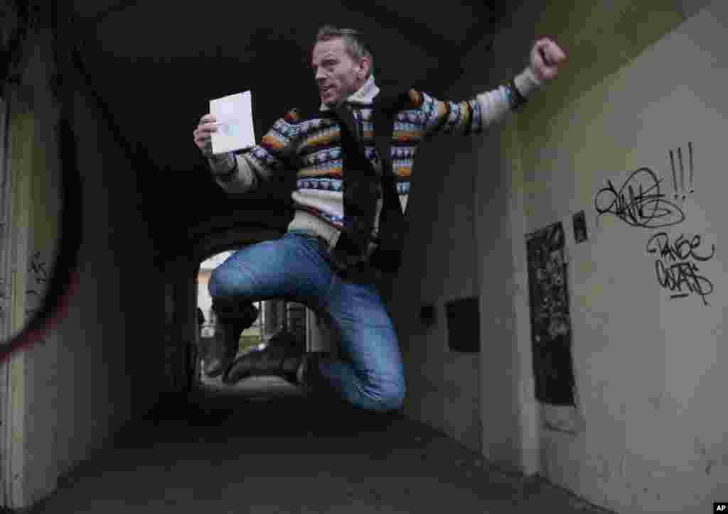 Greenpeace International activist Mannes Ubels of Netherlands jumps holding his passport as he celebrates getting permission to leave Russia, near the Federal Migration Service in St. Petersburg.