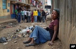 FILE - A relative wails on the floor of an alleyway near to the body of a man who had been shot in the head and who the crowd claimed had been shot by police, as the angry crowd shouts towards the police, in the Mathare slum of Nairobi, Kenya, Aug. 9, 2017.