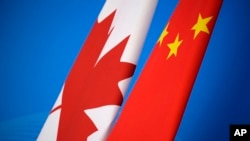 FILE - Flags of Canada and China are on display during for a China-Canada economic and financial strategy dialogue in Beijing, Nov. 12, 2018.