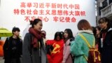 資料照：上海大學生在一幅宣傳習近平的大標語前照相後將一面中共黨旗收起來。（2017年11月19日）