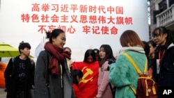上海大學生在一幅宣傳習近平的大標語前照相後將一面中共黨旗收起來。（2017年11月19日）