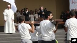 教皇方济各2015年6月21日在意大利都灵和年轻人见面时等待他们将一个木制十字架扛过来。此前教皇在都灵大教堂面对耶稣亚麻裹尸布做了祈祷。