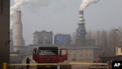 In this Dec. 30, 2016 photo, a truck leaves a sprawling complex that is a part of the Jiujiang steel and rolling mills in Qianan in northern China's Hebei province.