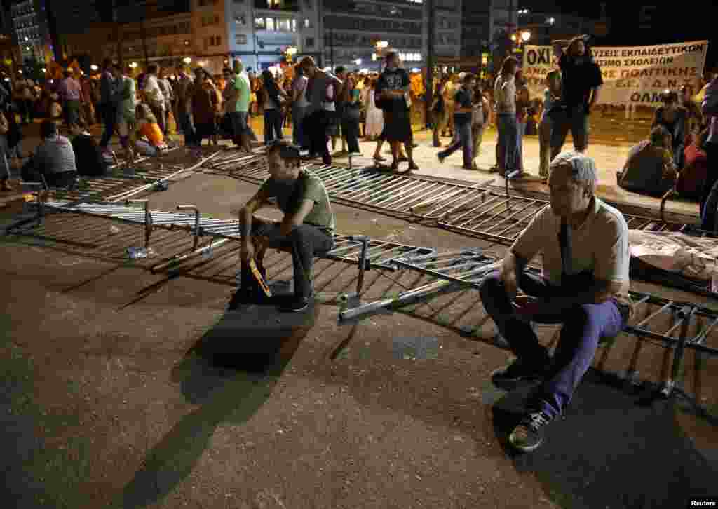 Demonstrators sit on a broken metal fence outside the Greek parliament during an anti-austerity protest in Athens, late July 17, 2013.