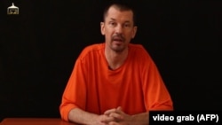 An image taken from a video released by the Islamic State (IS) group through Al-Furqan Media via YouTube allegedly shows British freelance photojournalist, John Cantlie, at an undisclosed location in which he says he is being held captive, Sept. 18, 2014.