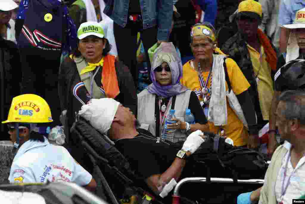 Anti-government protesters watch as an injured man is taken away from a clash site at a police compound, in the north of Bangkok, May 9, 2014.