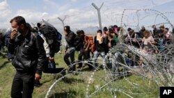 Migransts exit through a broken fence after a protest at the northern Greek border point of Idomeni, Greece, April 10, 2016.