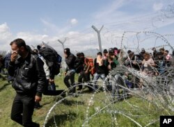 Migransts exit through a broken fence after a protest at the northern Greek border point of Idomeni, Greece, April 10, 2016.