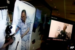 FILE - Video clips show China's jailed Nobel Peace laureate Liu Xiaobo lying on a bed receiving medical treatment at a hospital, left, and Liu saying wardens take good care of him, on a computer screens in Beijing, June 29, 2017.