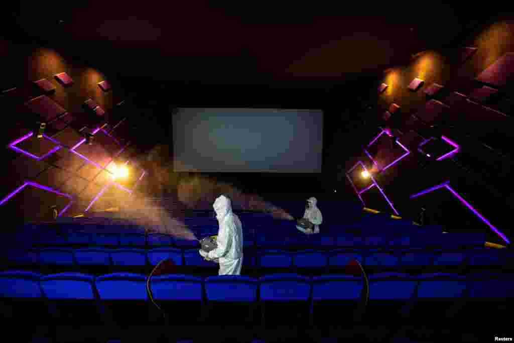 Workers in protective suits spray disinfectant inside a movie theater ahead of its reopening after the Thai government eased isolation measures to prevent the spread of the coronavirus disease (COVID-19) in Bangkok, Thailand.