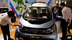 FILE - Visitors at the Beijing International Automotive Exhibition look at an electric vehicle by Chinese automaker Zotye on display in Beijing, China, April 26, 2016.