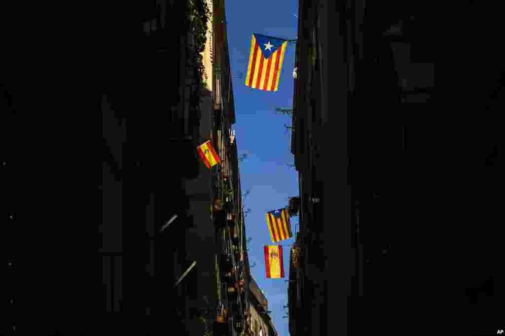 نمایی از پرچم های کاتالونیا و اسپانیا که از بالکن ساختمان های خیابانی در بارسلون اسپانیا به احتزاز در آمده اند.