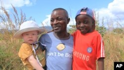 Razik Jaffalie porte ses deux fils à Machinga, au nord-est de Blantyre, au Malawi le 23 mai 2016. Il a dû abandonner son travail pour les protéger. 