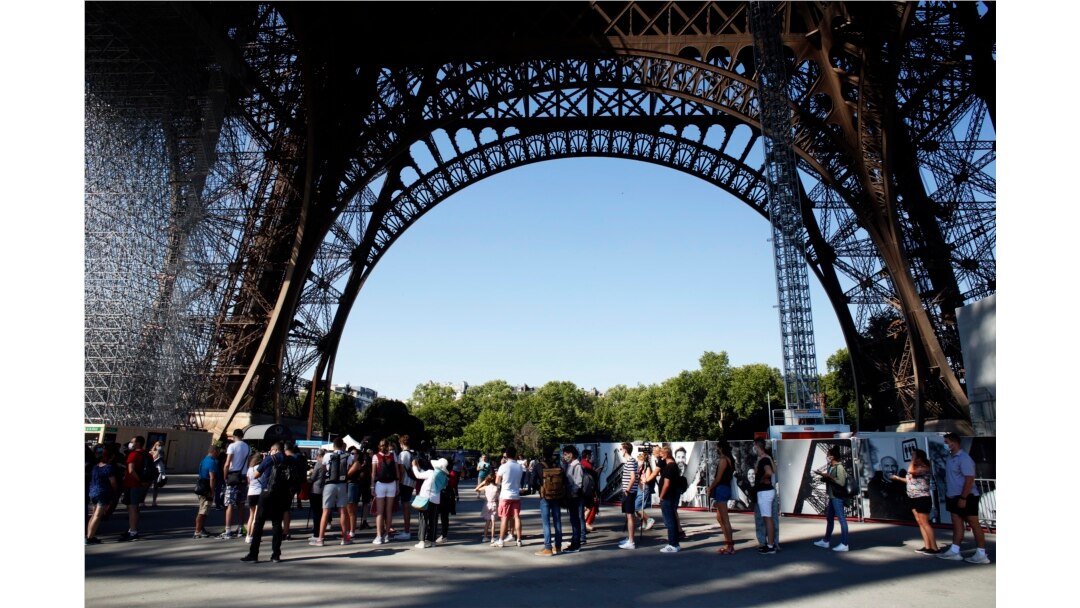 Para wisatawan antre di bawah Menara Eiffel, Paris, Kamis, 25 Juni 2020. (Foto AP / Thibault Camus)