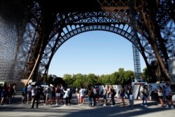 Para wisatawan antre di bawah Menara Eiffel, Paris, Kamis, 25 Juni 2020. (Foto AP / Thibault Camus)