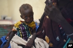 FILE - Nyagoah Taka Gatluak, a severely malnourished 1-year-old child, sits on her mother's lap in the Doctors Without Borders clinic in Leer town, South Sudan, Dec. 15, 2015 — the two-year anniversary of the beginning of South Sudan's civil war.
