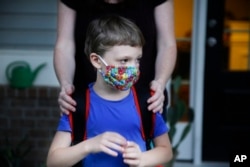 Rachel Adamus holds her son Paul, 7, in front of their house before the bus arrives for the first day of school on Monday, Aug. 3, 2020, in Dallas, Georgia, USA.