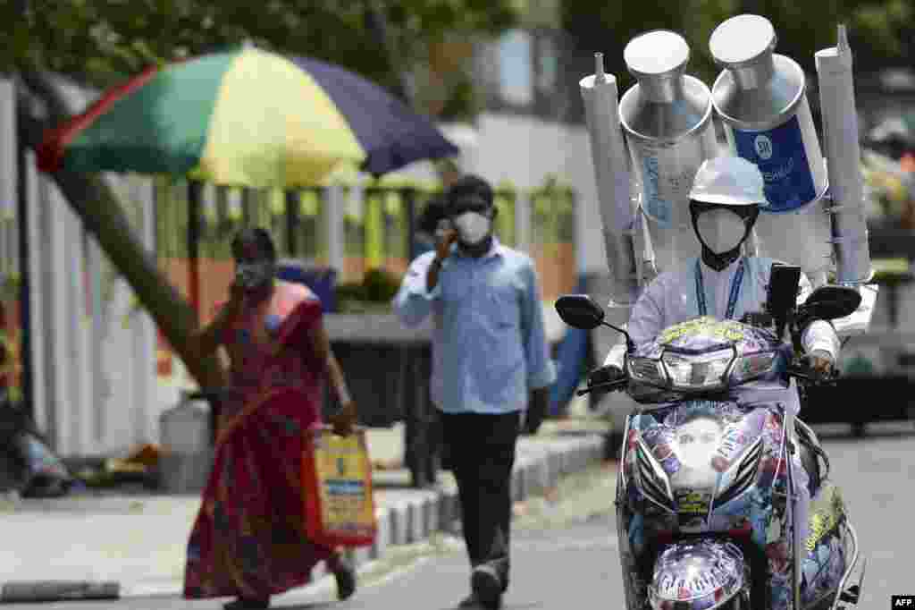 A volunteer rides along a road with a mock Covishield and Covaxin vaccine vials on the back of his scooter during a Covid-19 vaccination awareness campaign, in Chennai, India.