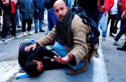 A demonstrator takes care of a man wounded by police during a protest in Tunis, Jan. 23, 2021. Tunisia is extending its virus curfew and banning demonstrations as it tries to stem a rapid rise in infections and calm tensions from protests.
