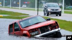 An abandoned vehicle is seen half submerged in a ditch next to a nearly flooded freeway, under downpours from Hurricane Ida on Sunday, Aug. 29, 2021, in Bay Sain Louis, Mississippi.