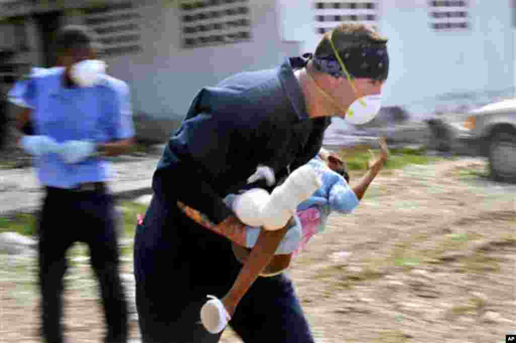 U.S. Coast Guard Petty Officer 3rd Class Cameron Croteau carries an injured Haitian girl to an awaiting Coast Guard HH-60 Jayhawk helicopter in Port-au-Prince, Haiti, 19 Jan 2010 - U.S. Coast Guard